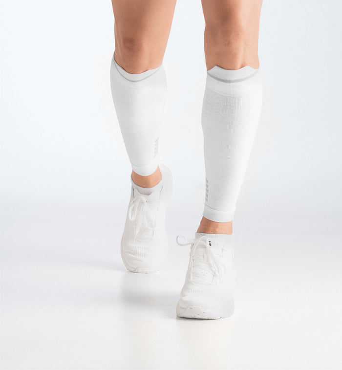 Deportista usando pantorrilleras de compresión blancas para recuperación muscular
